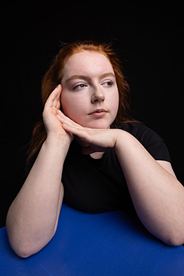 Megan sitting with eyes open, hands to her face. 