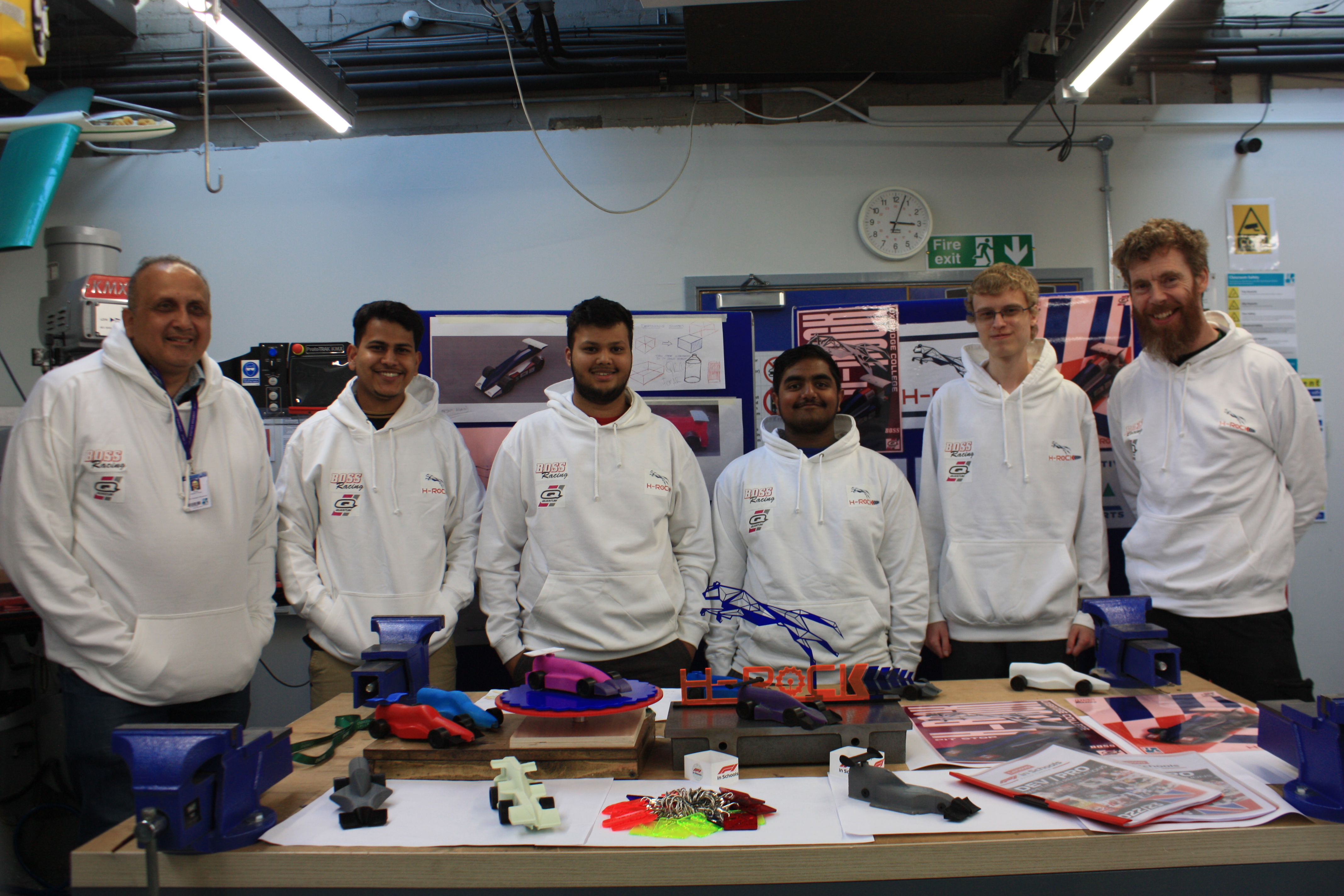4 members of the F1 in Schools development team standing around a workshop table
