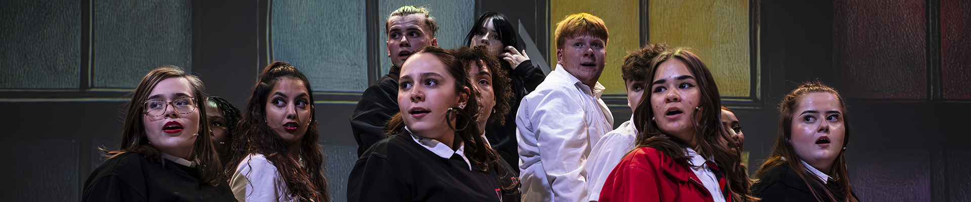 Praxis Performing Arts students performing Our House: the musical. The cast are grouped on stage all looking to their right, facing side on.