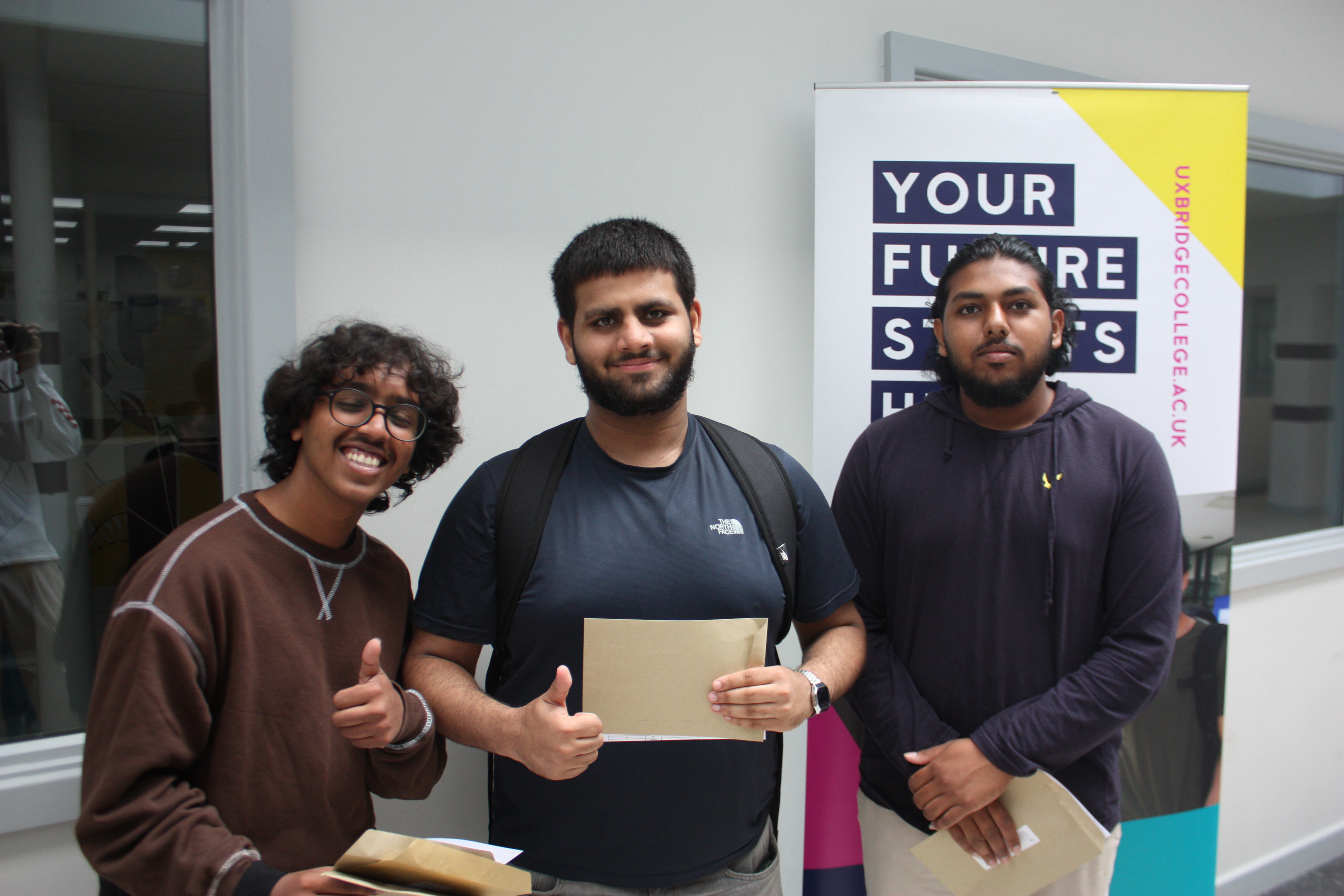 Picture of 3 male BTEC students collecting their results