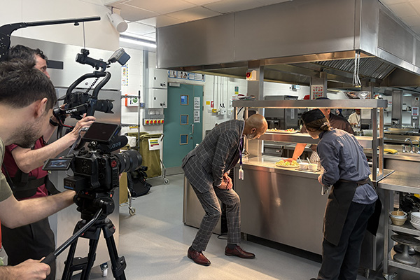 Meet the Principal Video behind the scenes footage - Clive talking to Uxbridge Culinary students in the Revisco kitchen. There is a film crew in the foreground.
