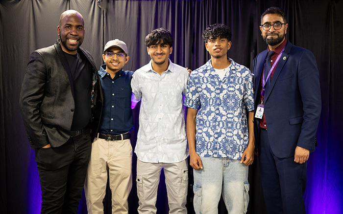 Male Uxbridge College Engineering students winning an award at the HRUC Skills Competition Awards Ceremony, presented by Yaseen Akhtar - Managing Director of WLIoT with Action Jackson (the host) - they are standing in a group smiling.