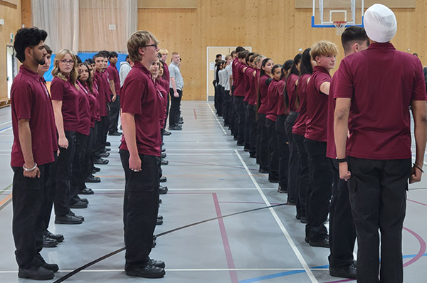 Uxbridge College Uniformed Services students at their Graduation Parade lined up - they are all wearing red tops and black trousers.