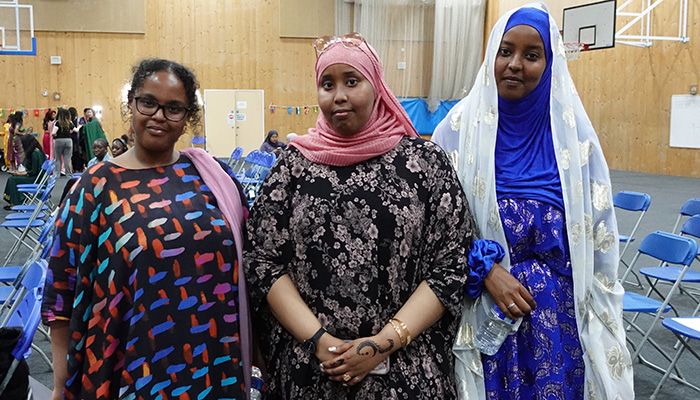 Three Female Uxbridge College students dressed to celebrate the Celebration Day Cultural Event in their own cultural dress. They are wearing colourful dresses and standing in the Sports Hall.    