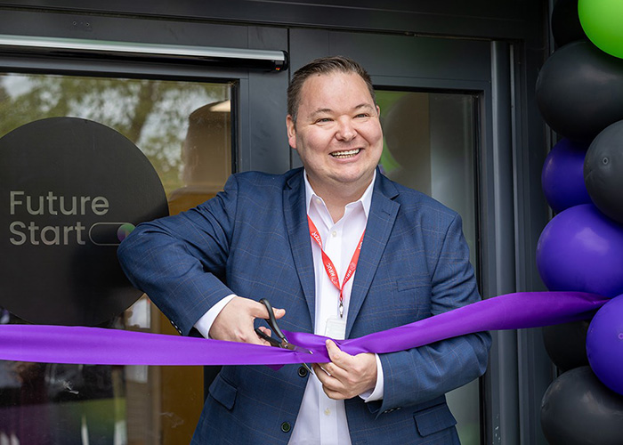 Andrew Western MP, Minister for Employment cutting the purple ribbon at the new Future Start youth employment hub. There are black, green and blue balloons behind him with a window with the Future Start logo.